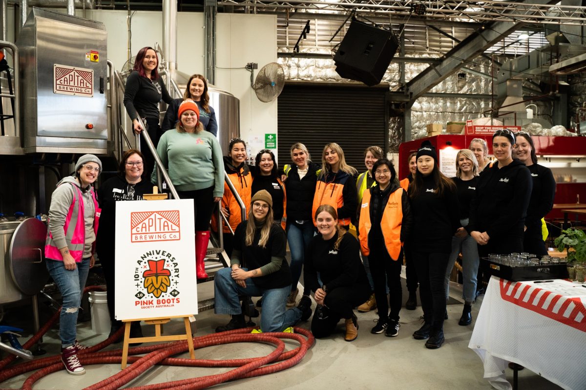 group posing in front of brewing equipment