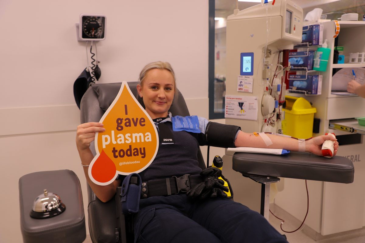 A woman in a chair holds up a sign `I gave plasma today'.