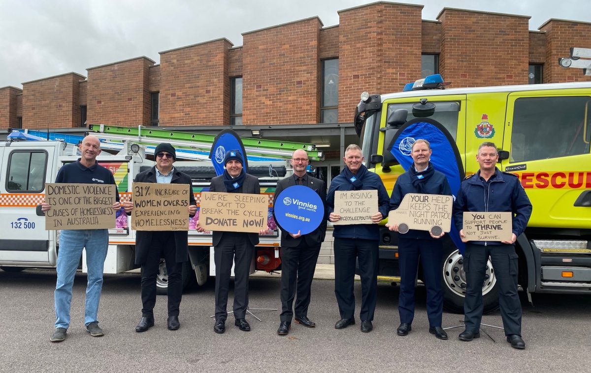 Seven men hold up signs supporting Vinnies.