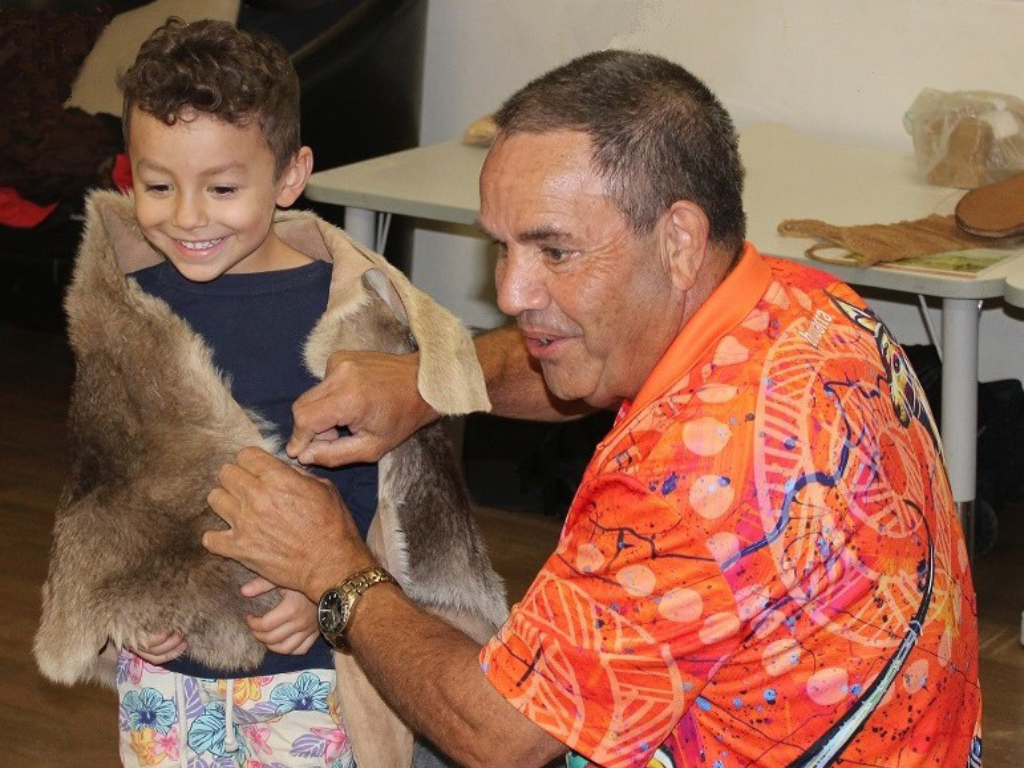 Larry Brandy wraps an animal skin around a young boy.