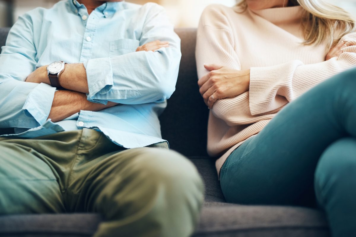 Man and woman on couch with crossed arms