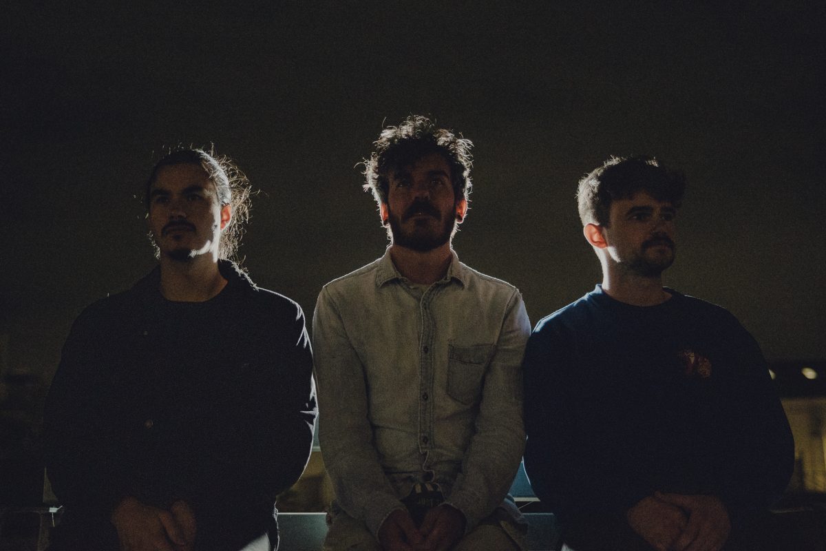 Three people sitting in near darkness