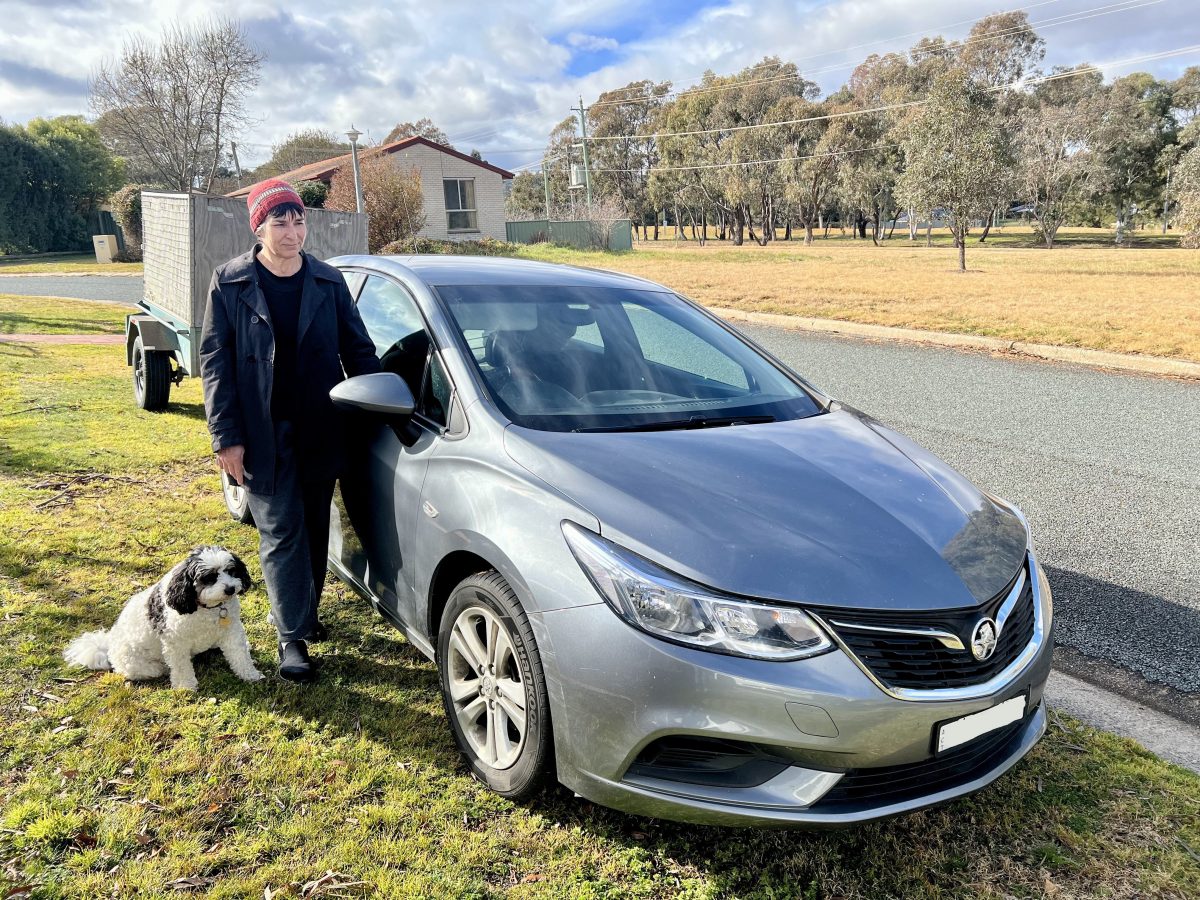 Woman with a very cute dog standing next to a car