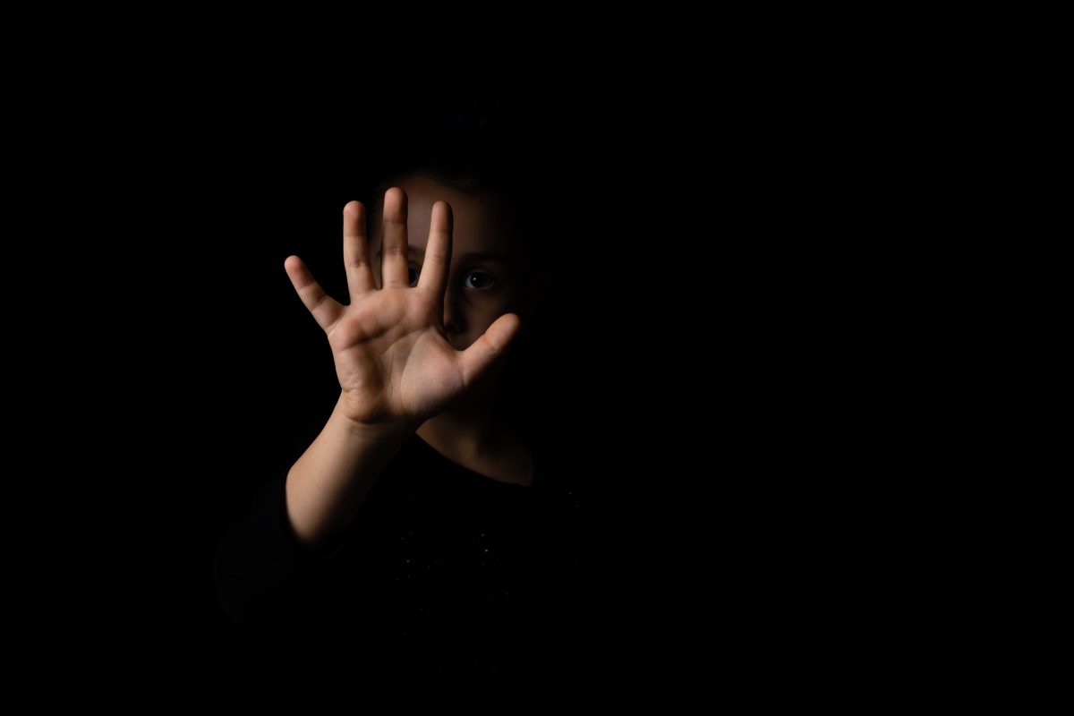 Darkened image of a woman with her hand reaching out.