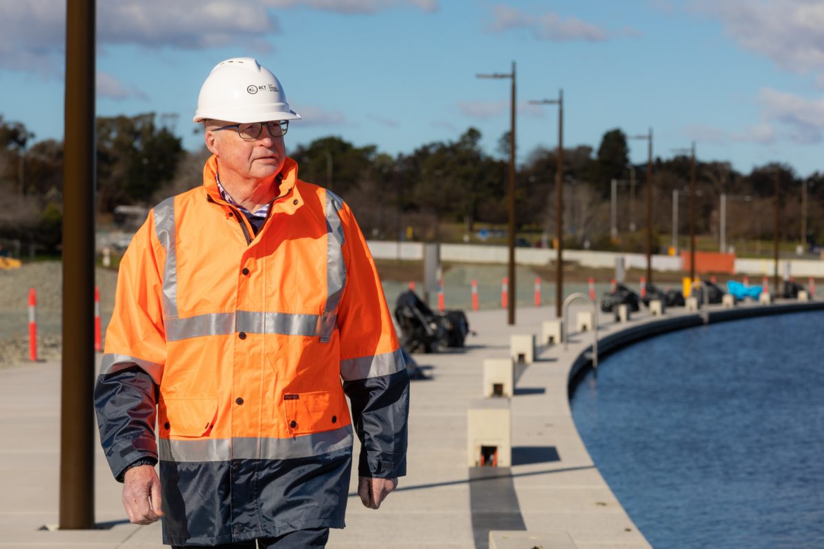 man in hi-vis walking next to Lake Burley Griffin