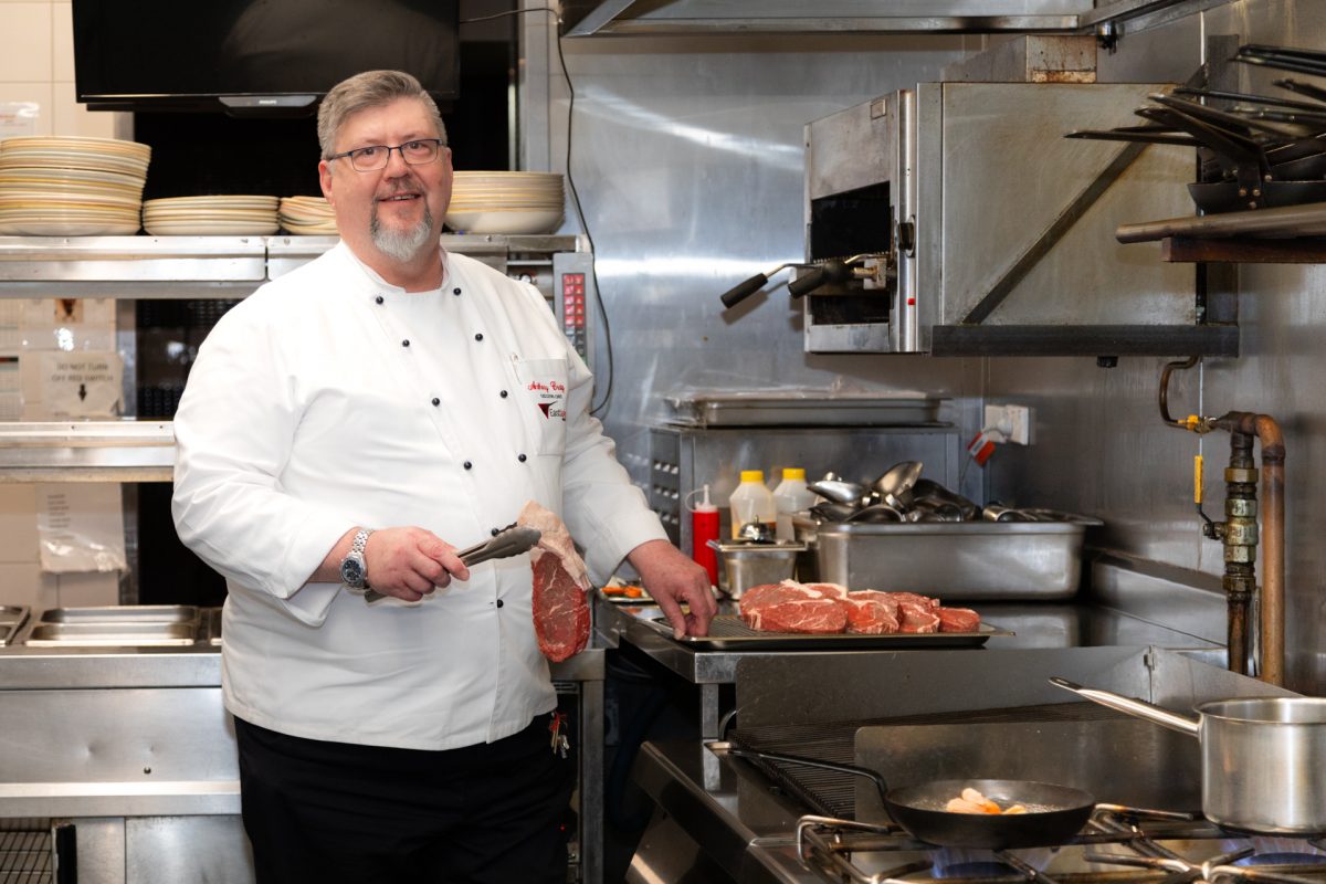 Chef holding raw steak with tongs