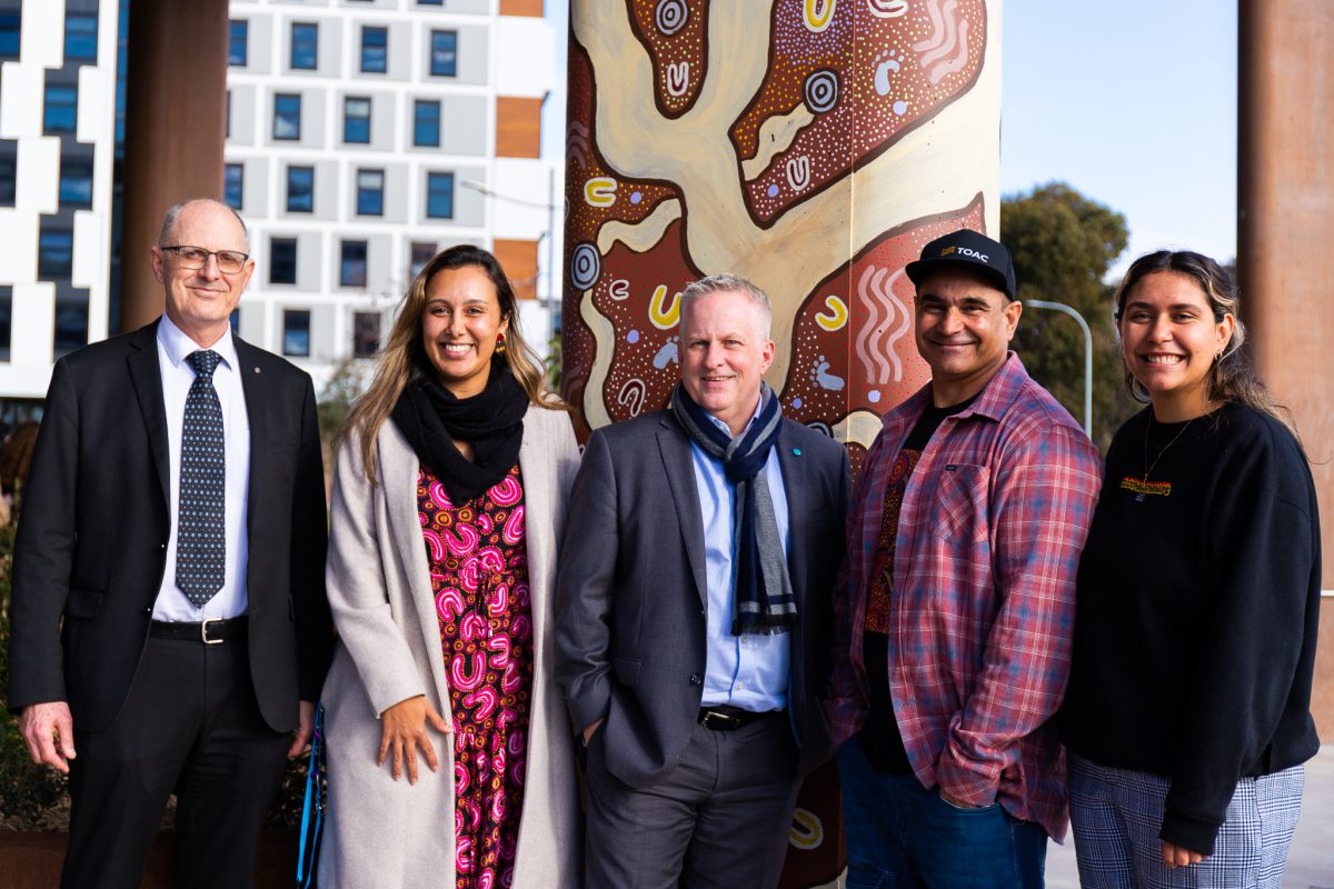 Group of people with Indigenous pole art