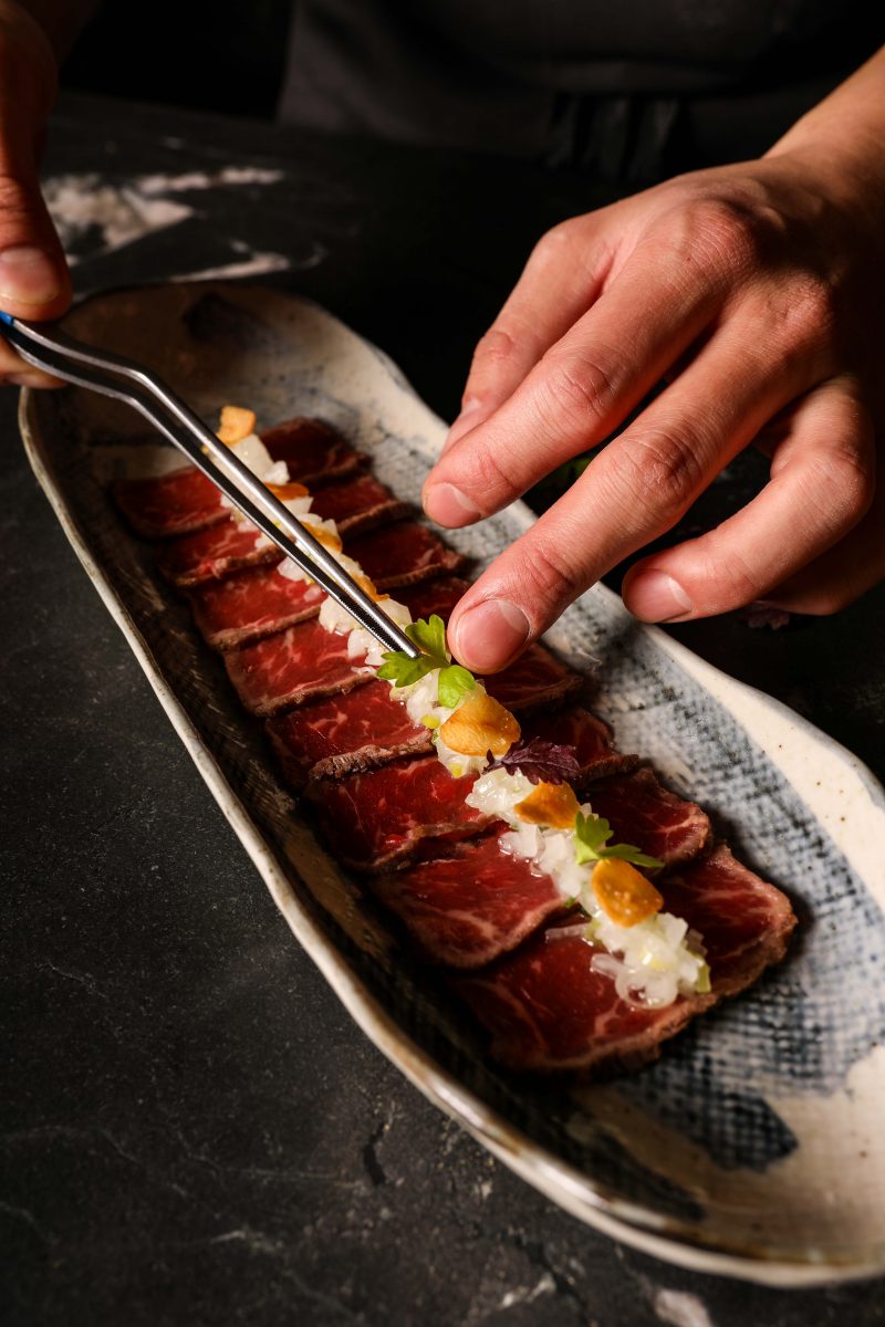 Chef places microherbs on meat with tweezers