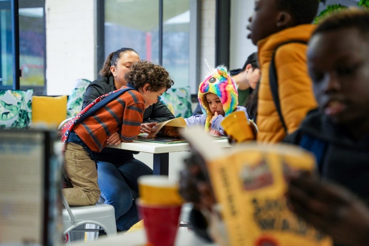 Parent reading to child in a busy cafe.