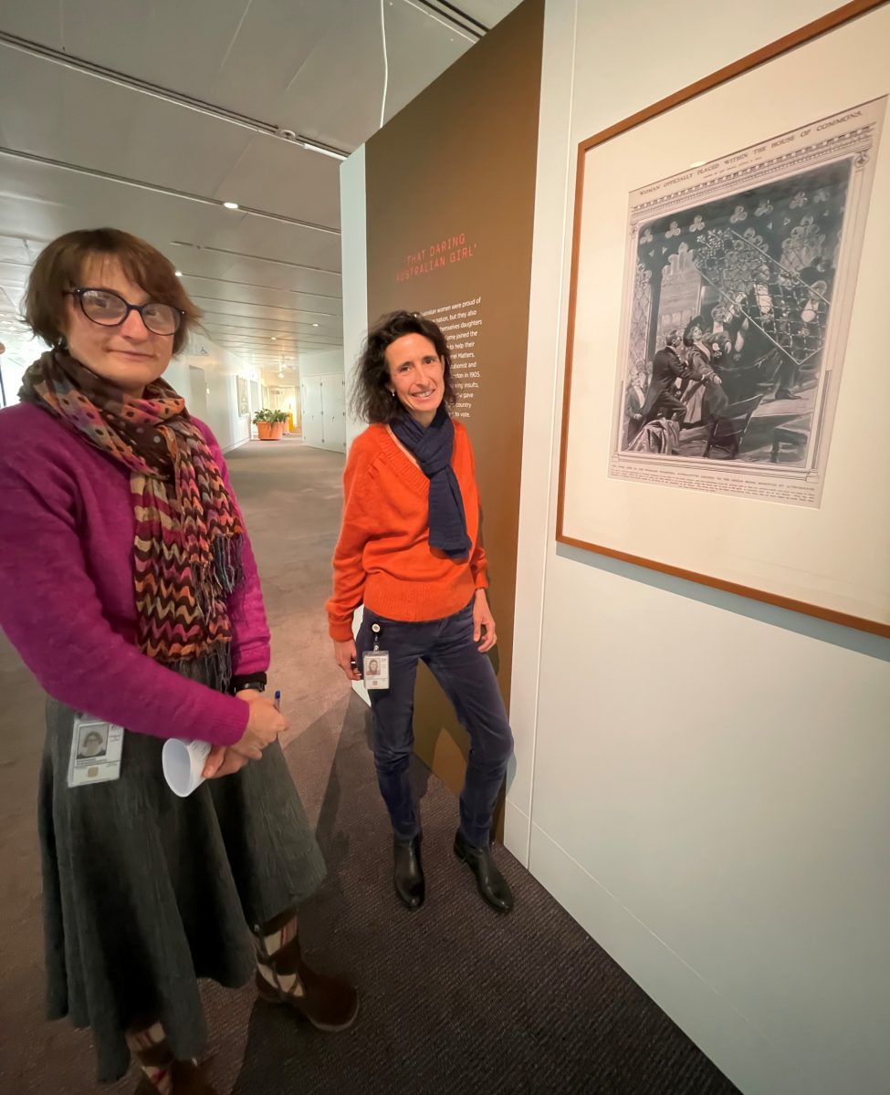 Two women in front of painting. 