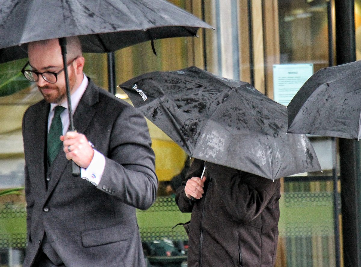 Man and woman with umbrellas outside court