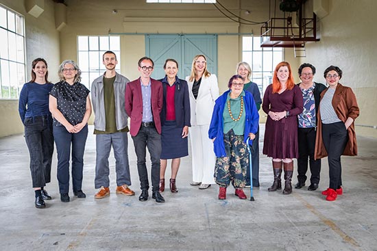 Eleven people standing in a warehouse