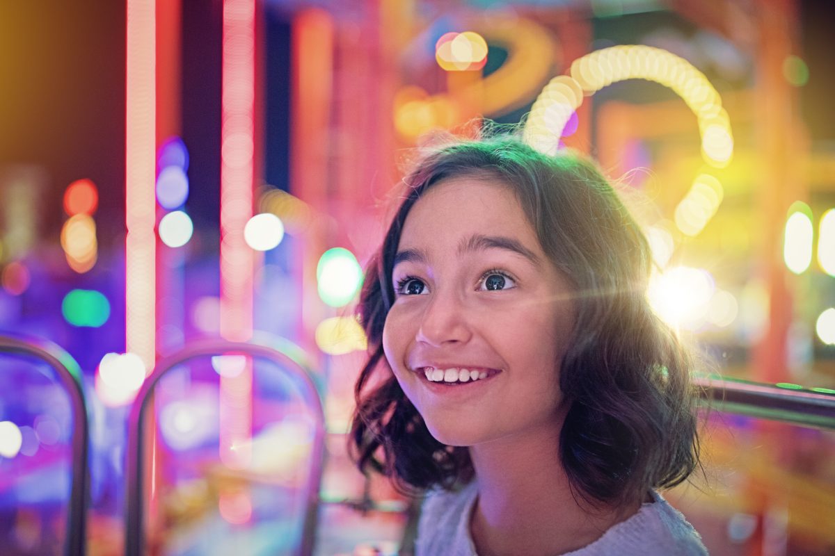 Girl smiling with carnival ride lights in background