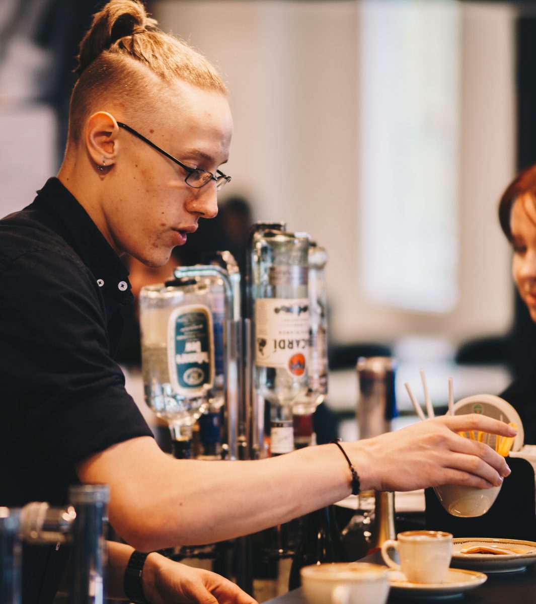 Young barista putting coffee on the pass at a cafe