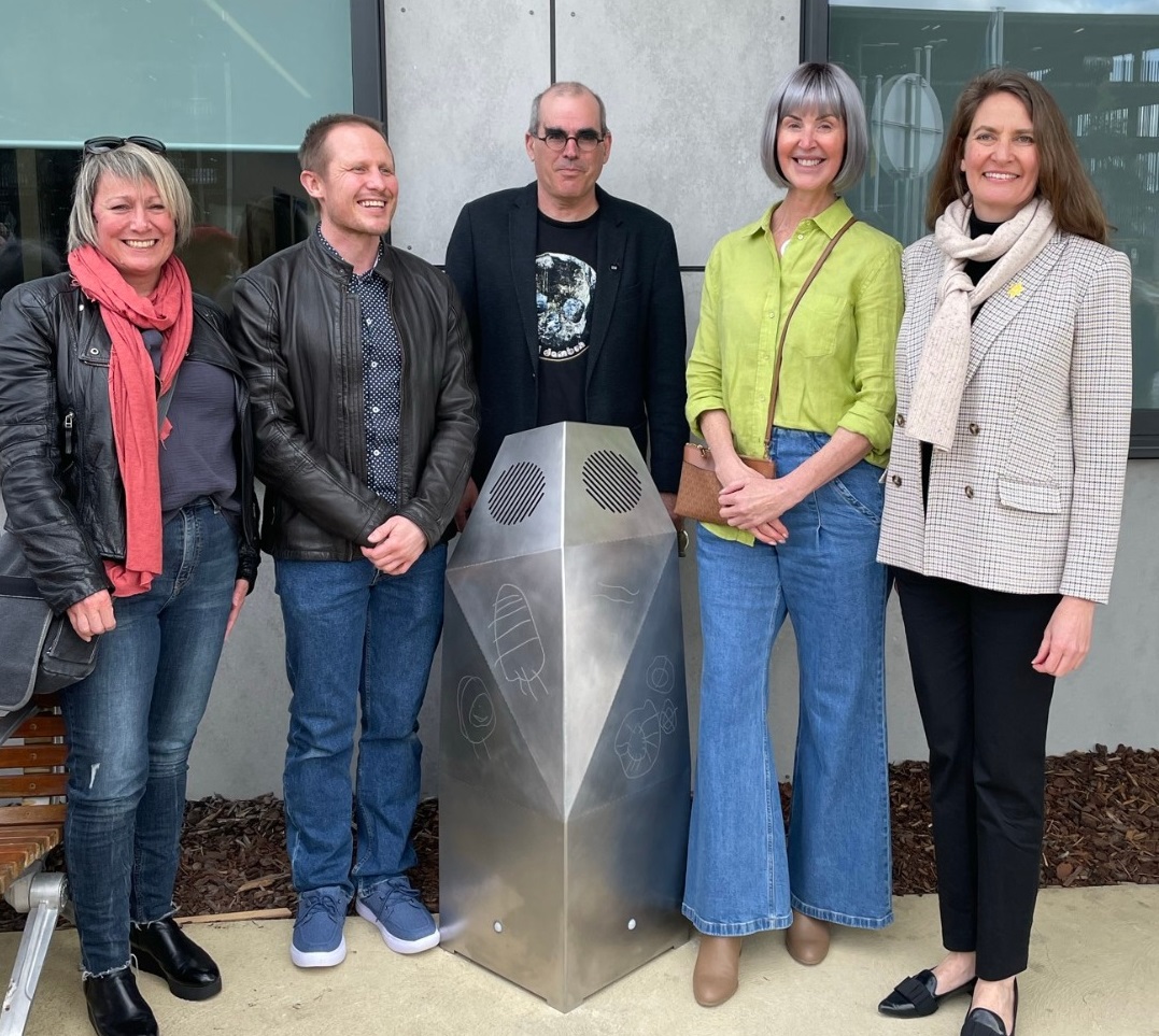 three women and two men stand around sculpture.