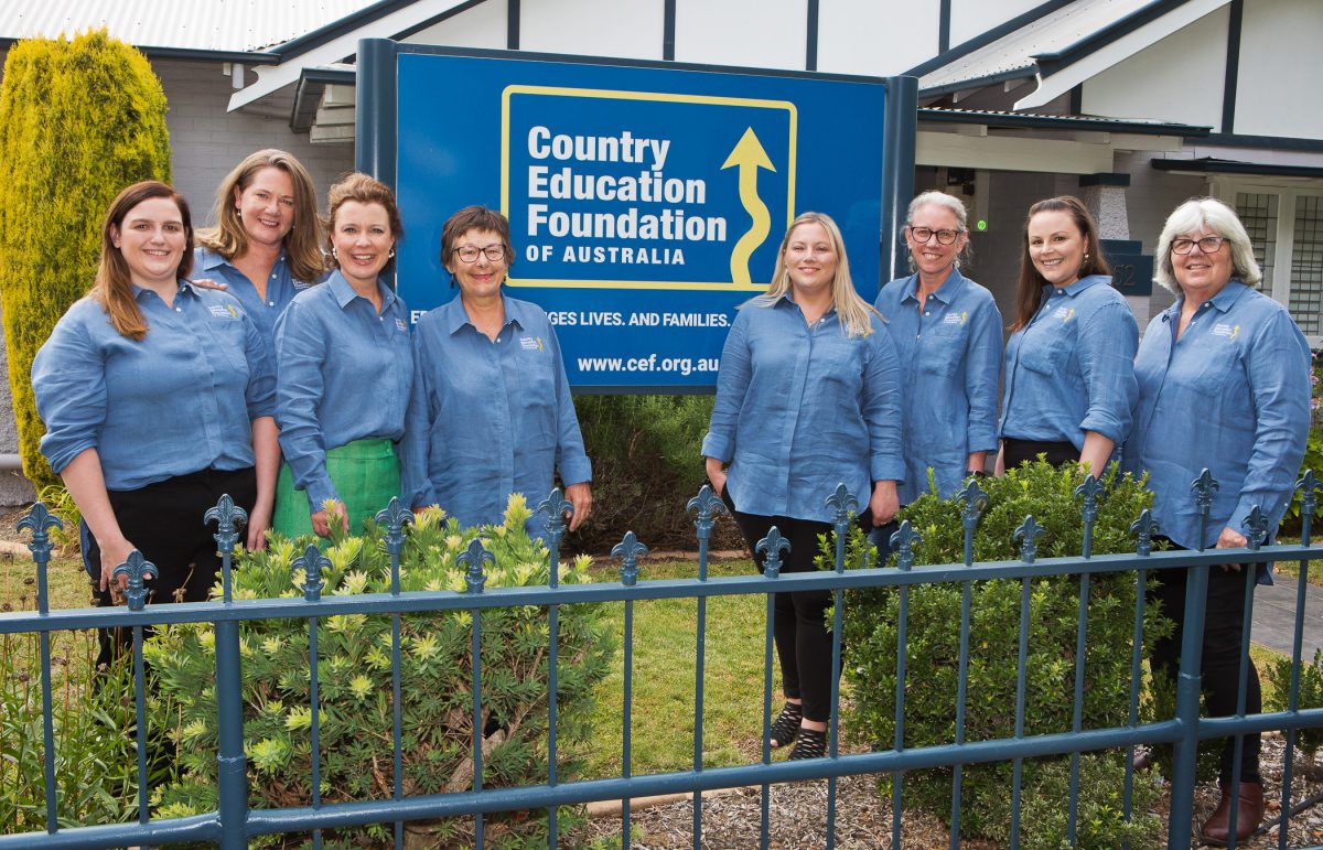 Eight women in uniforms standing in front of a Country Education Foundation of Australia sign
