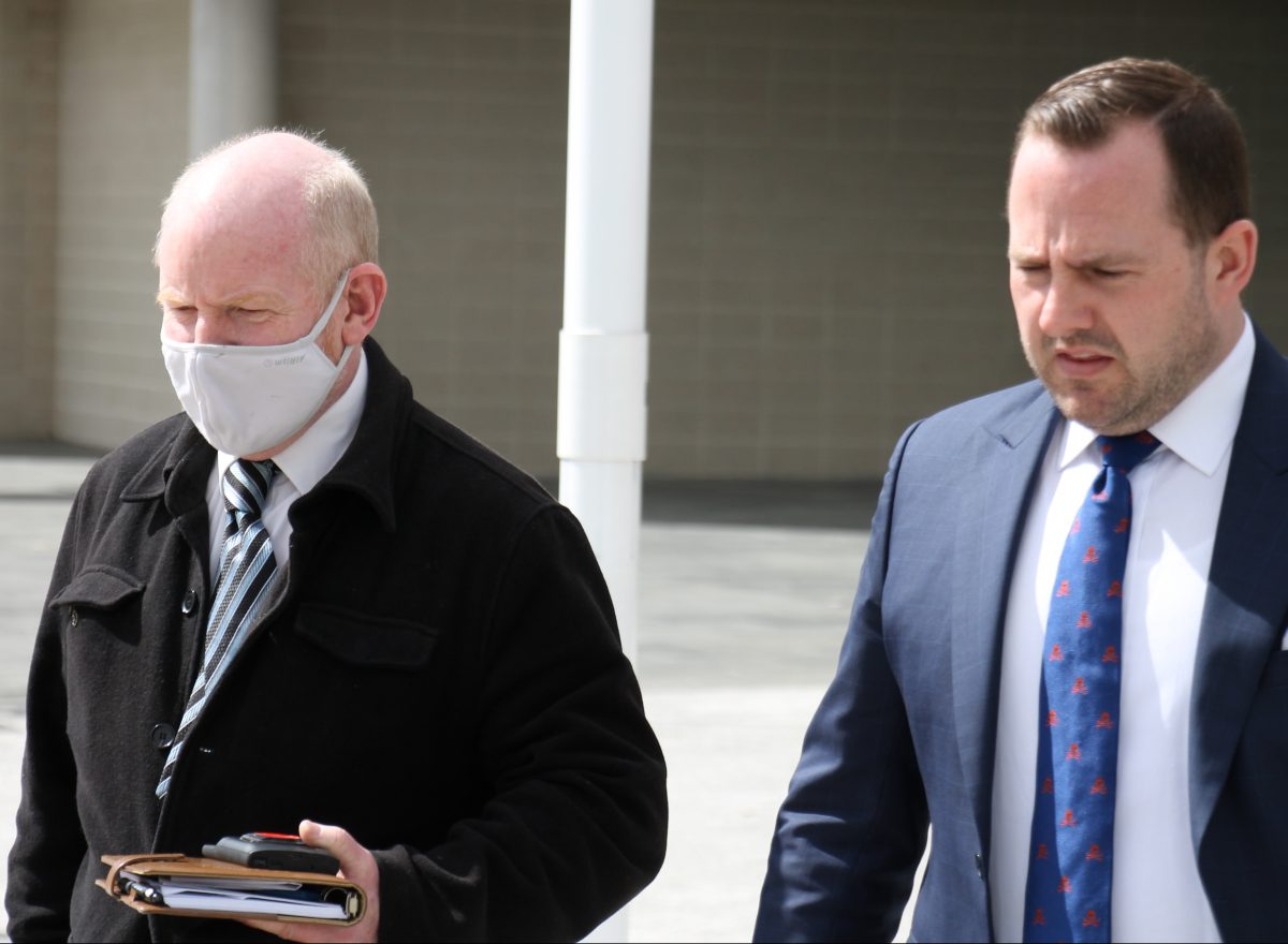 Man in mask leaving court with his lawyer