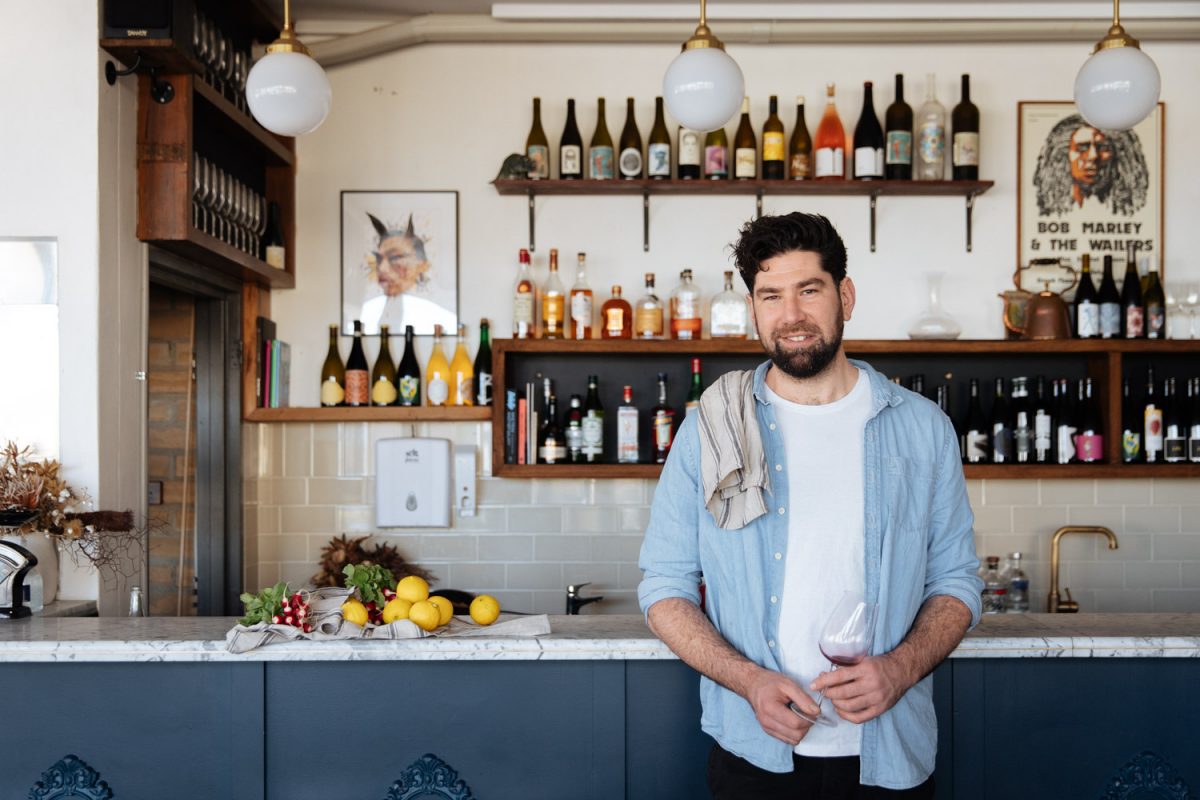 Bearded man in front of wine shelf