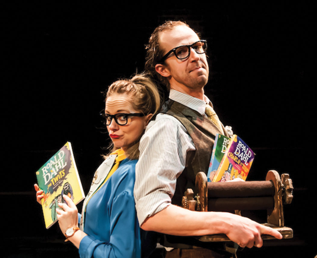 Two actors on stage holding books