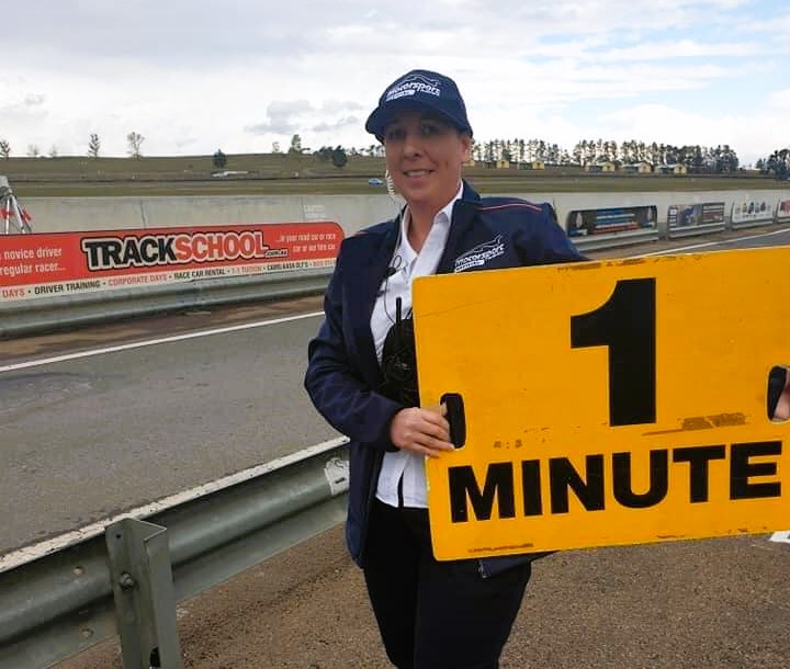 Woman holding sign at a race track