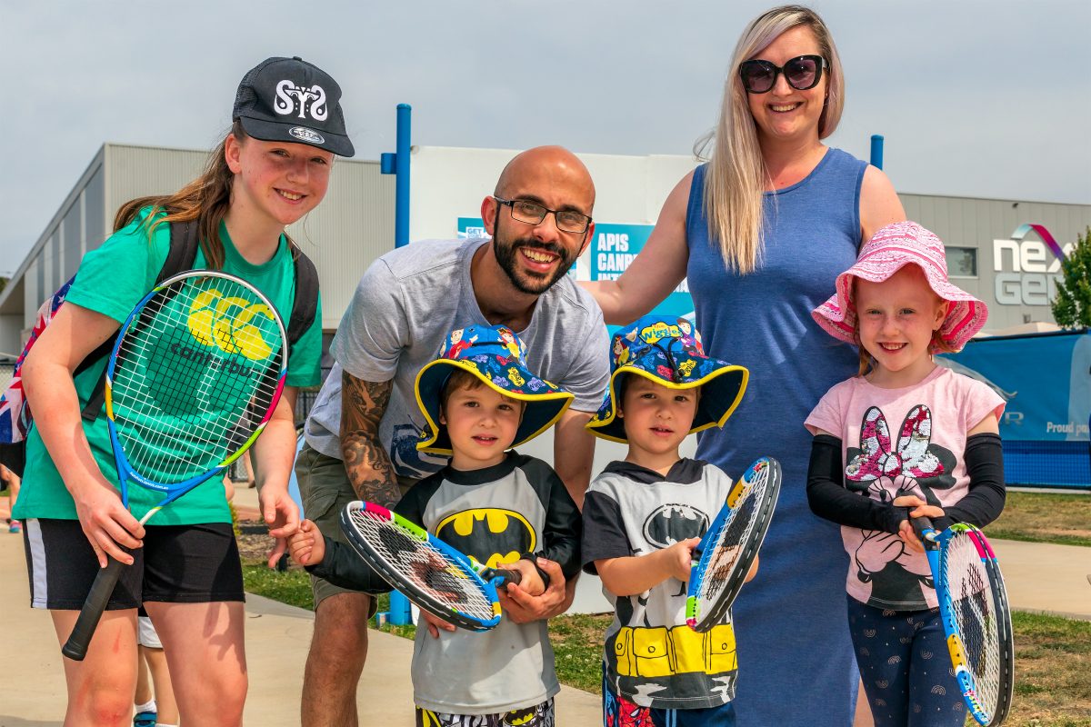 Family gathered and holding tennis racquets 