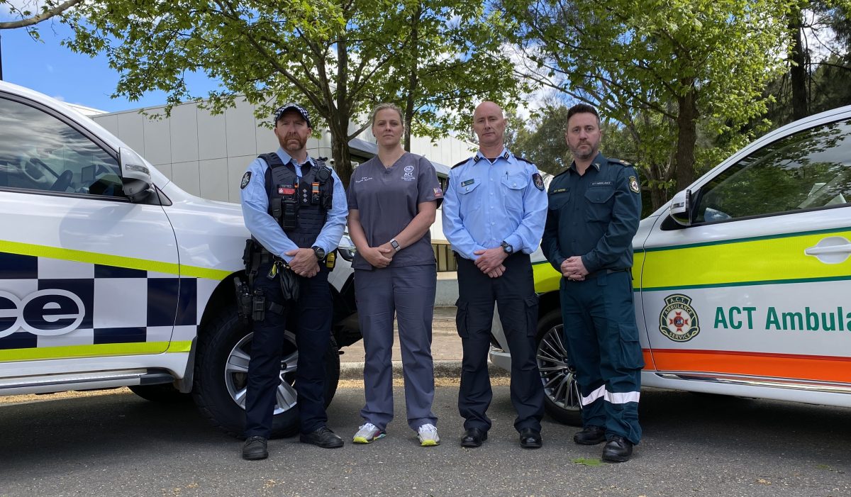 Four first responders in front of vehicles