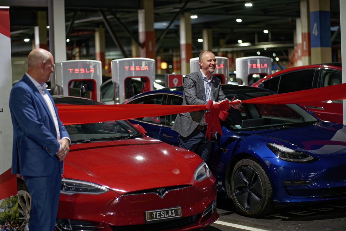 Andrew Barr cutting a ribbon in front of new Tesla cars