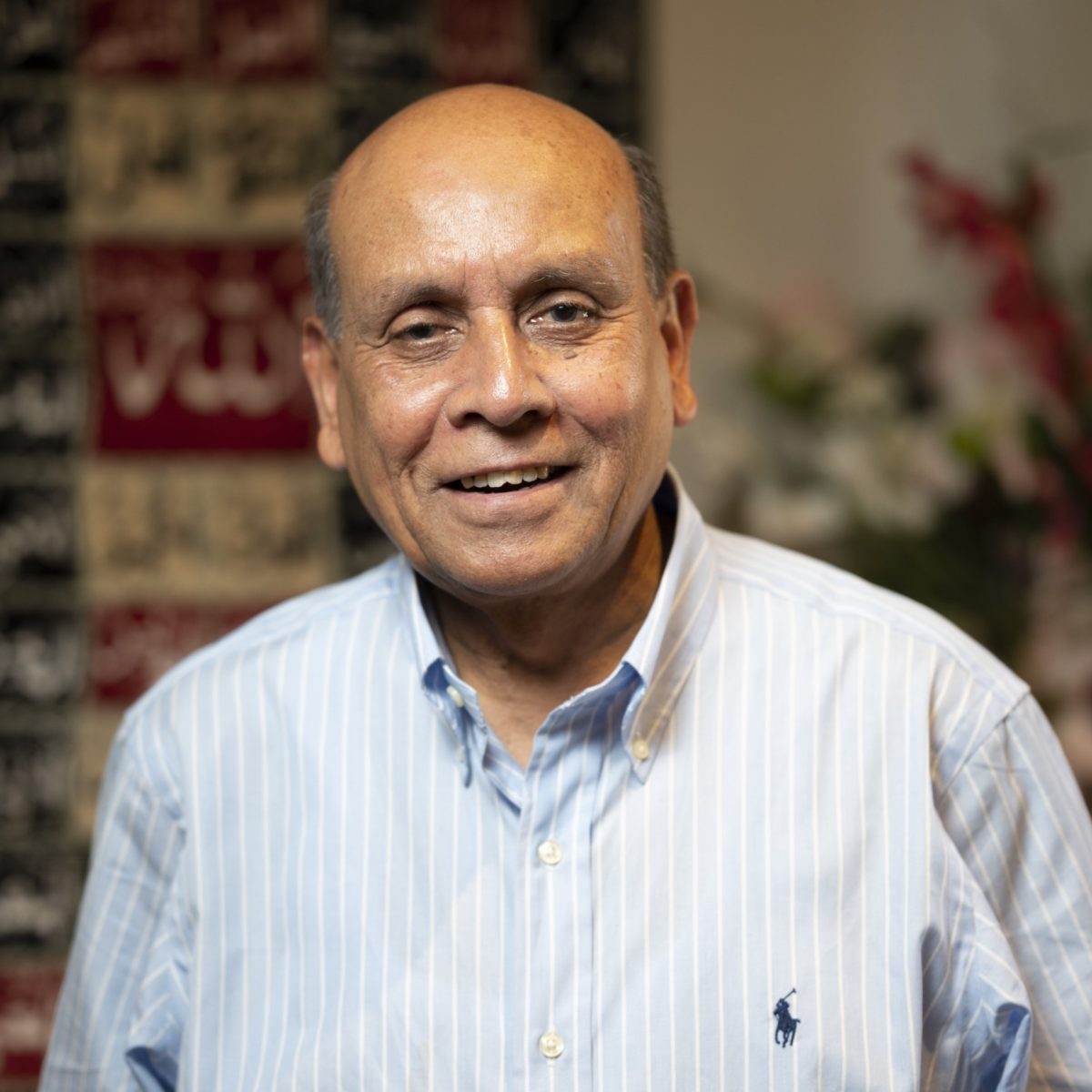 A man wearing a blue and white striped shirt smiling at the camera