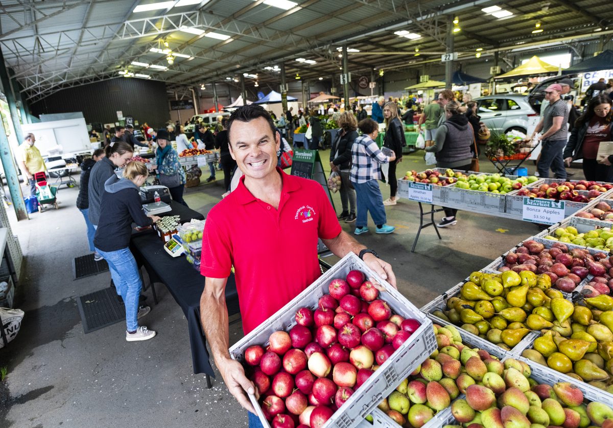 man holding crate of apples at the markets