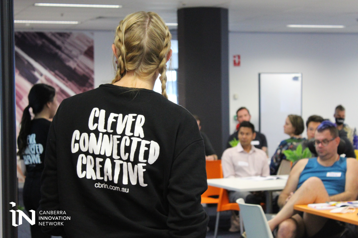 Woman from back at Canberra Innovation Network workshop, wearing a shirt that says Clever Connected Creative