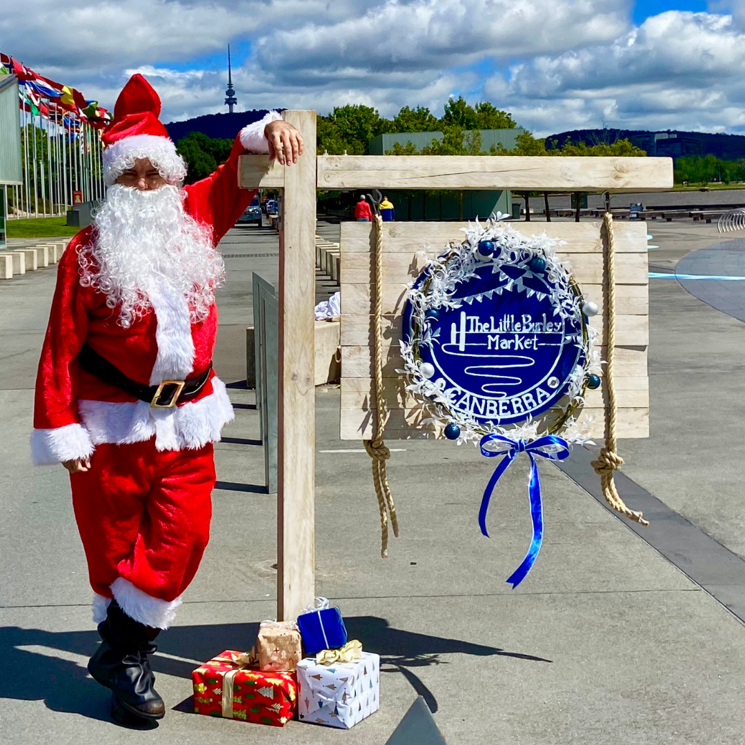 santa standing next to the Little Burley Market sign