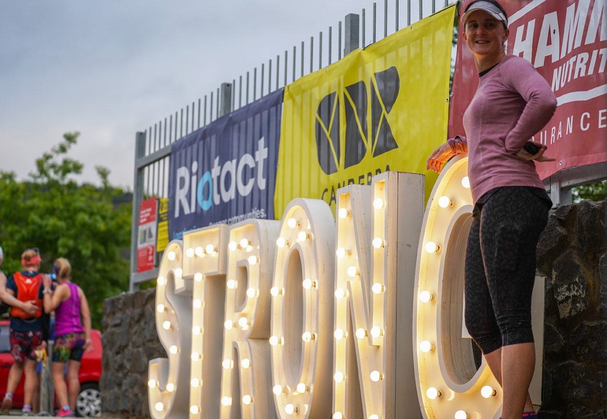 Woman standing next to giant led light letters spelling the word STRONG at the 2022 Stromlo Running Festival