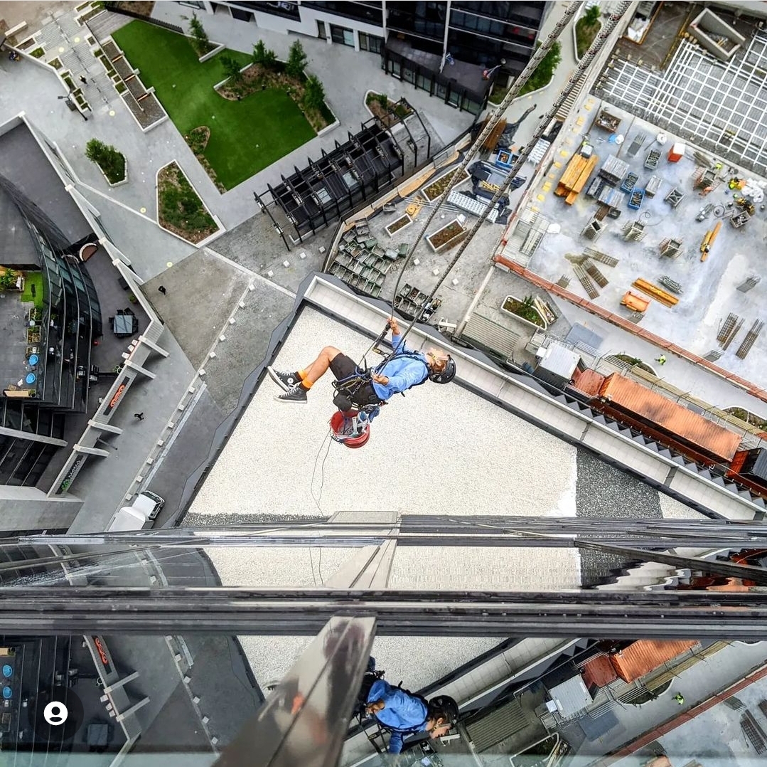 Man hanging on a rope off a building