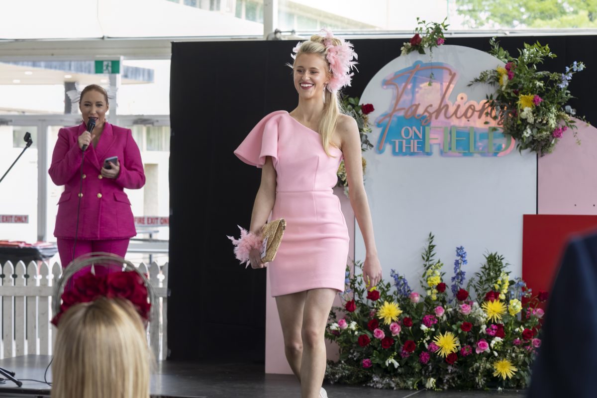 lady in pink dress walking down a runway