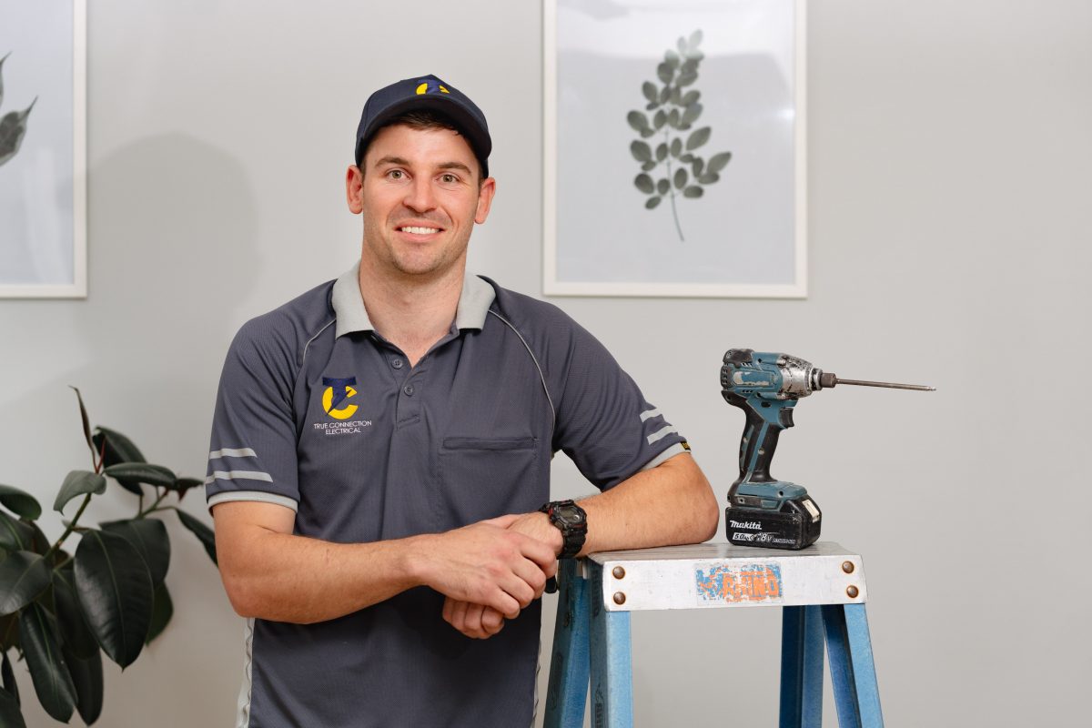 Electrician standing next to power drill and ladder