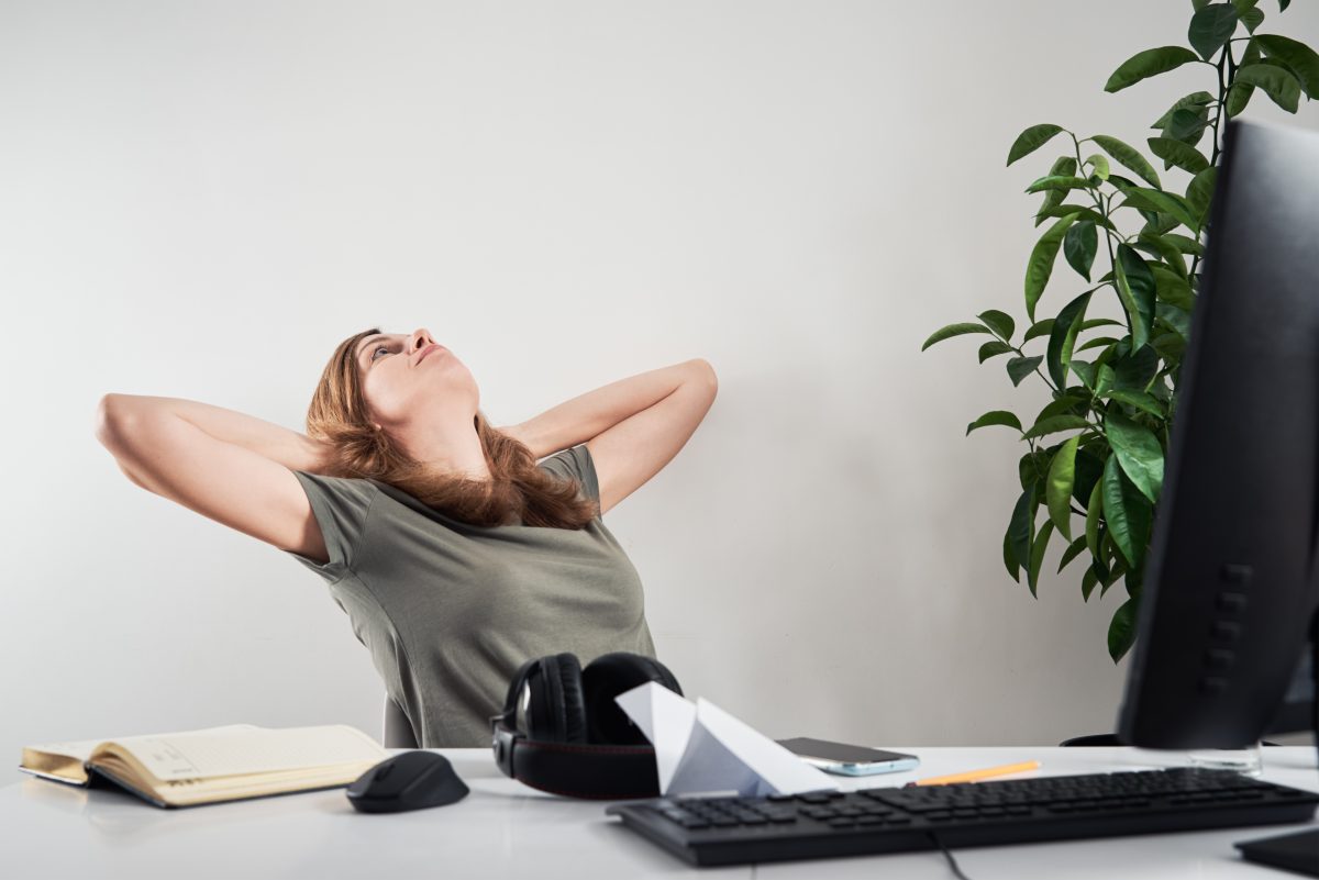 woman leaning back in her office chair with hands behind her head