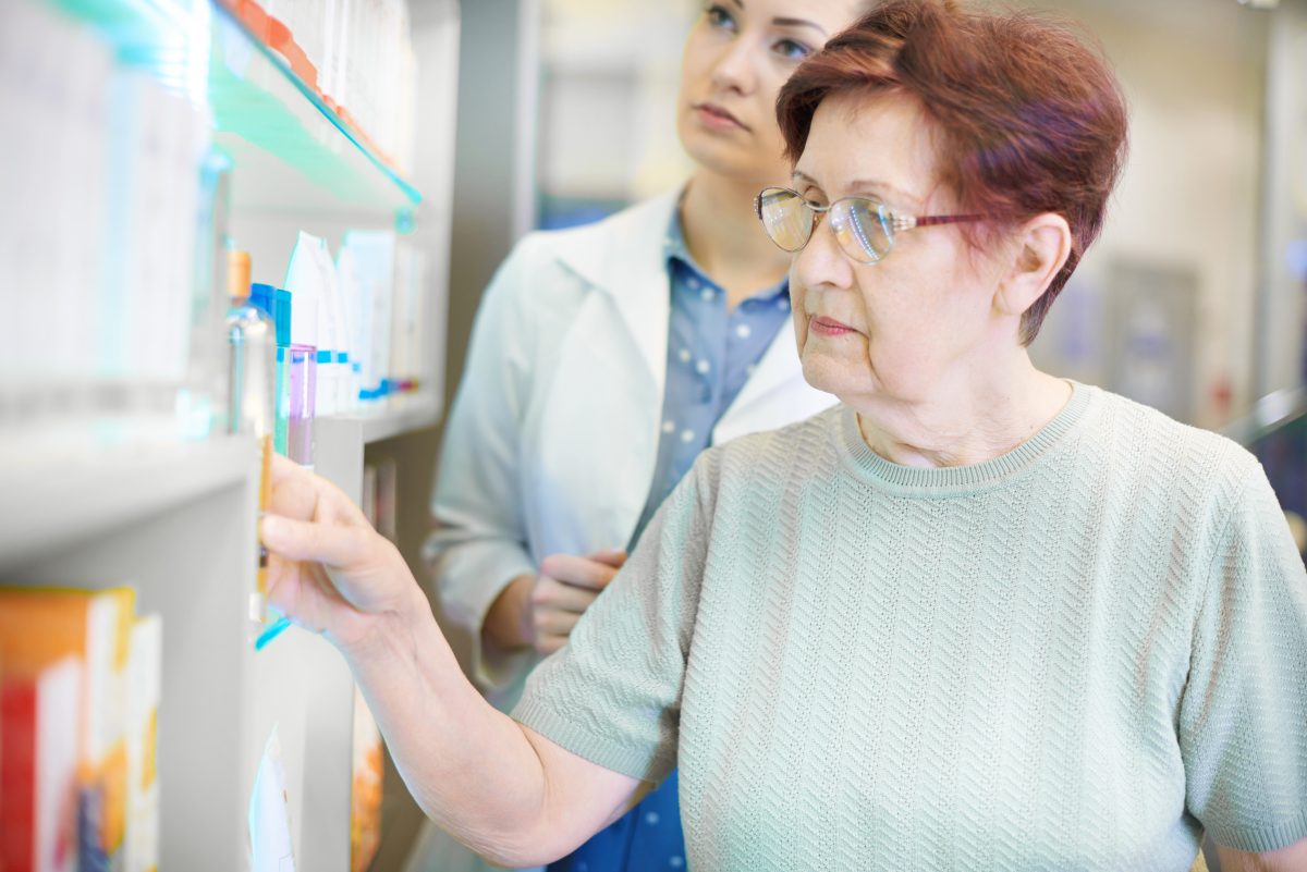 Senior Australian women selects medication of the shelf at a pharmacy