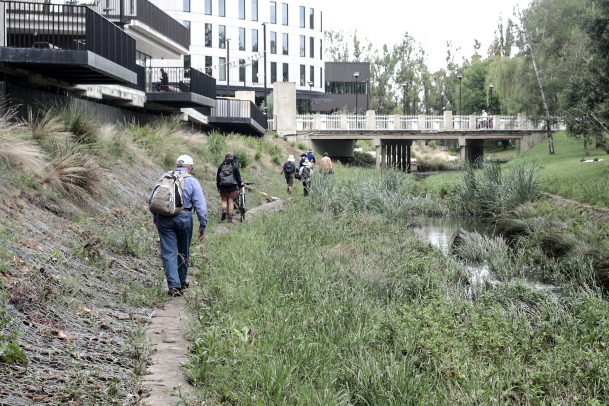 People walk along a waterway in Canberra