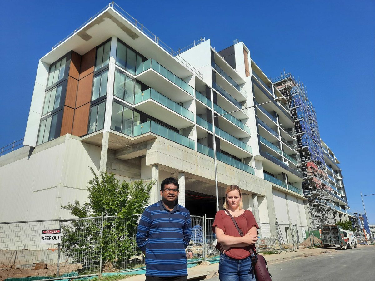 Two people outside apartment construction site