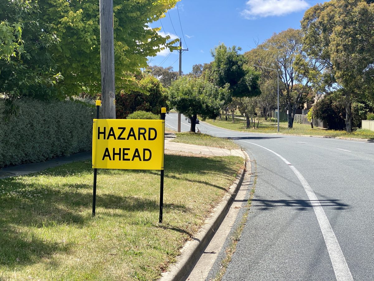 Yellow 'hazard ahead' sign on side of suburban street