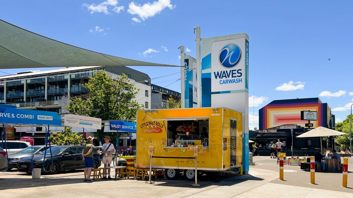 yellow food truck on the street next to a car wash