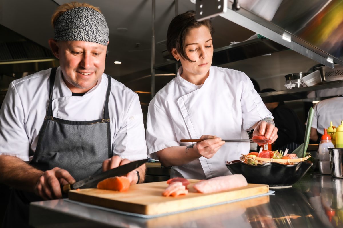 two chefs slice sashimi