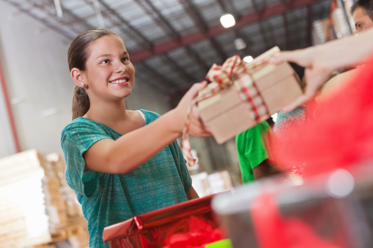 Happy little girl donating Christmas gifts at charity toy drive