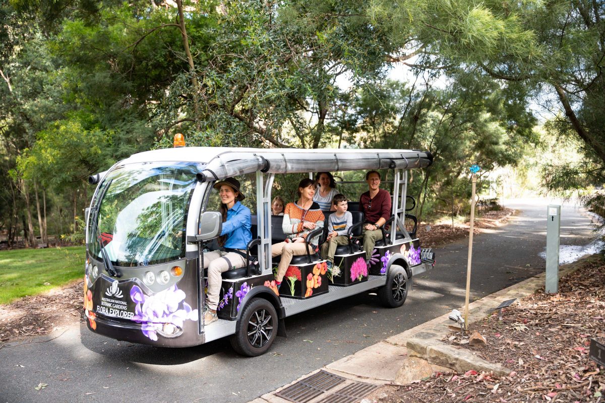 A tour bus full of people traveling at The National Botanic Gardens in Canberra