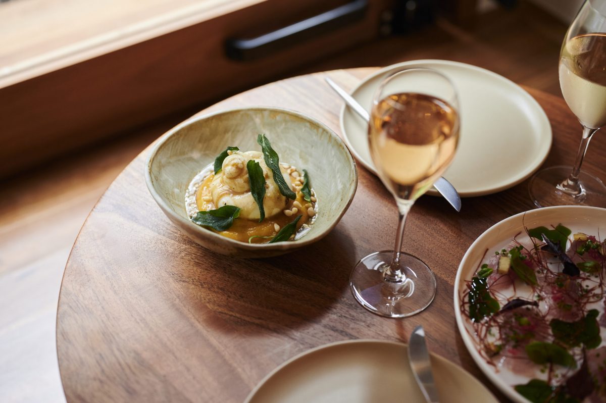 Bowl of burrata and pumpkin with wine glass