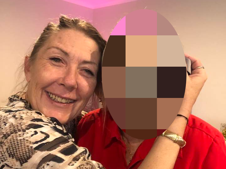 two women hugging; one face has been pixelated