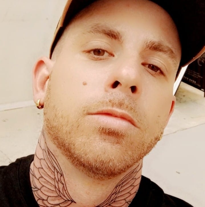 Man with neck tattoos wearing a cap