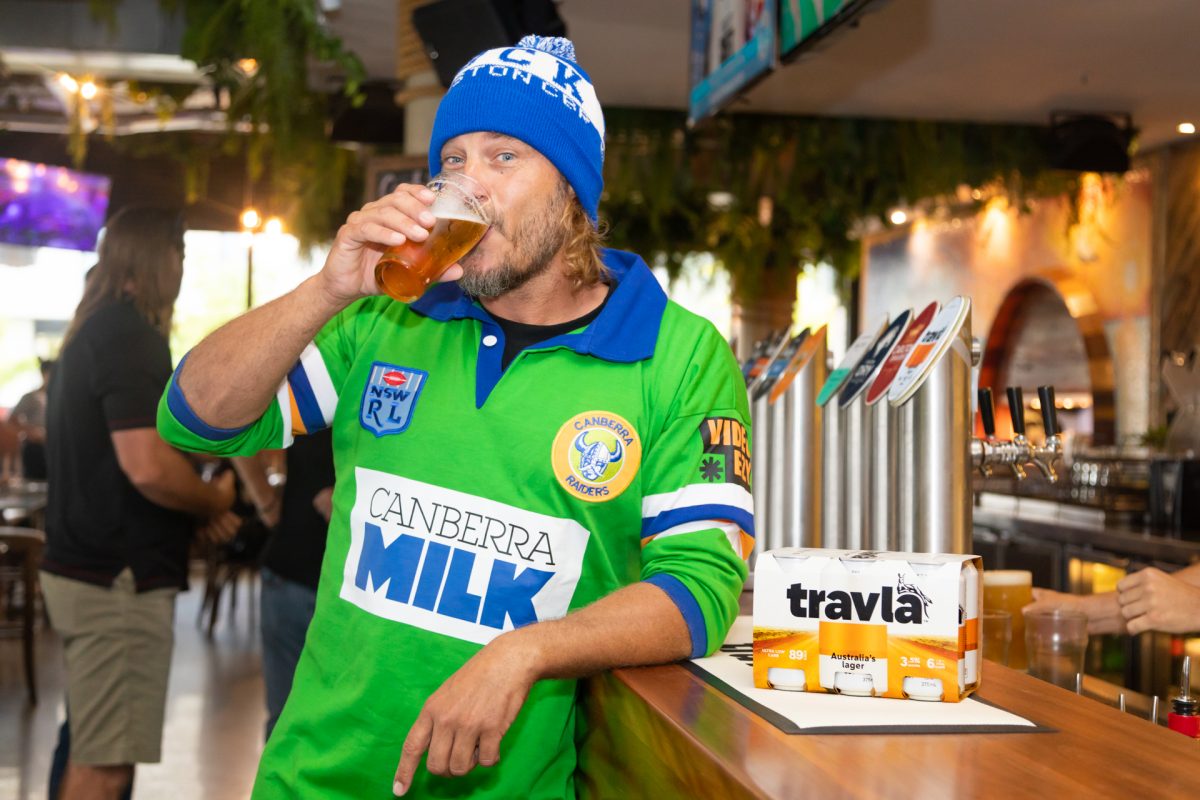 man drinking a beer in a Raiders jersey