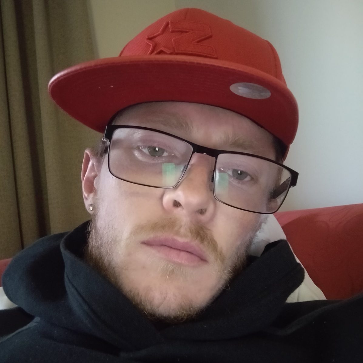 selfie of man with glasses and red hat