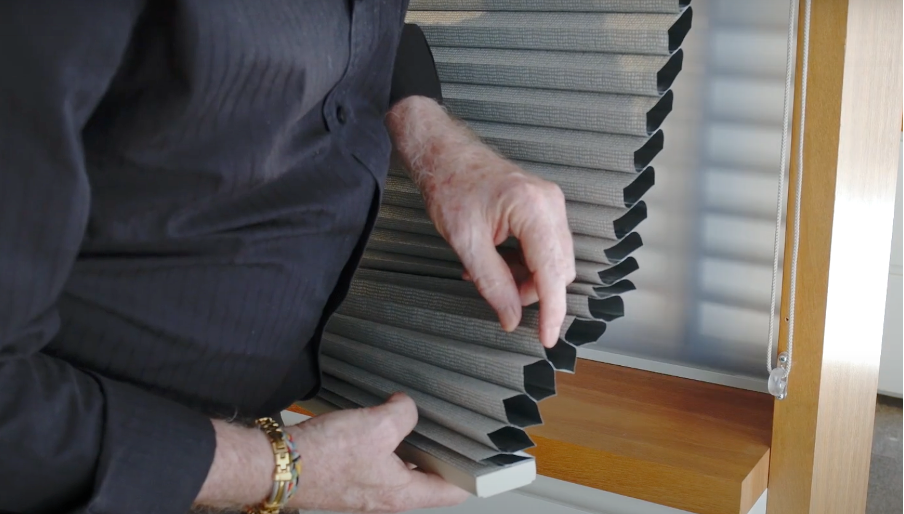 Martin Smith shows the foil lining inside a room darkening honeycomb blind at the Regency Knights showroom